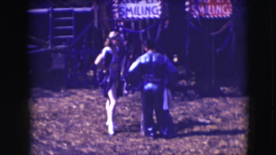 At the 1948 Sarasota Ringling circus, a costumed woman and uniformed man stand near a partially visible SMILING sign.