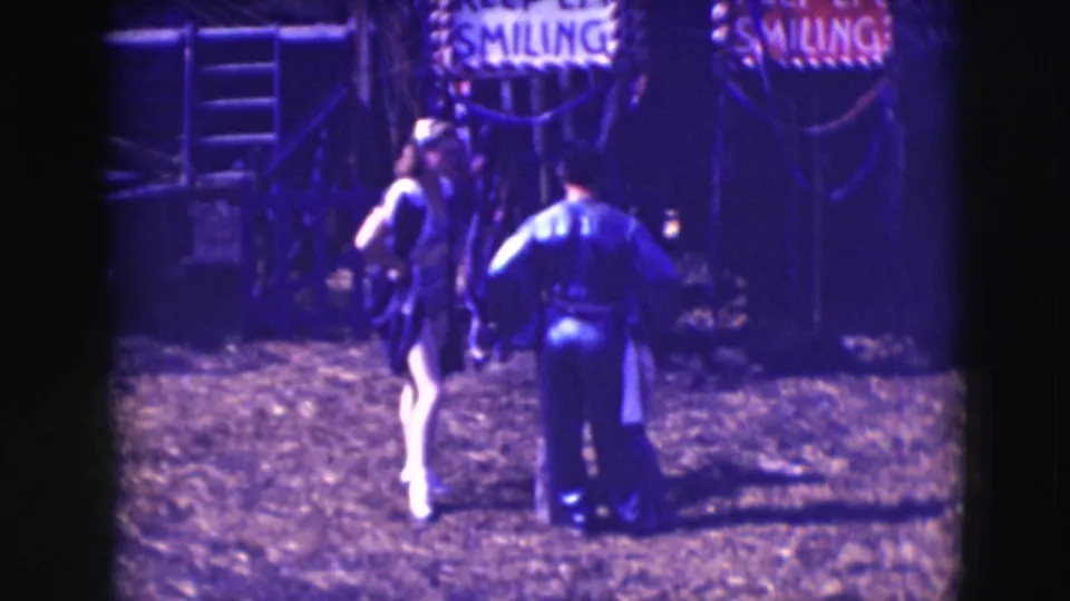 The closing frame shows a costumed woman and uniformed man near the partially visible SMILING sign at the Sarasota circus grounds.