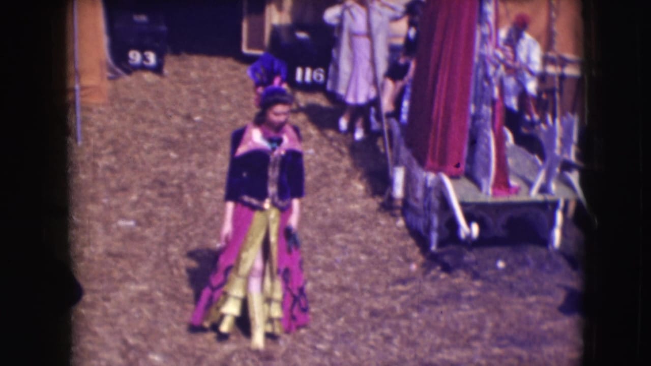 1948 Ringling Brothers Sarasota footage showing a performer in purple and yellow costume walking through a backstage dirt area.