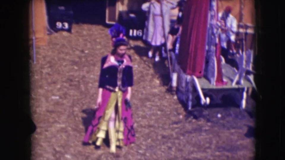 1948 Ringling Brothers Sarasota footage showing a performer in purple and yellow costume walking through a backstage dirt area.