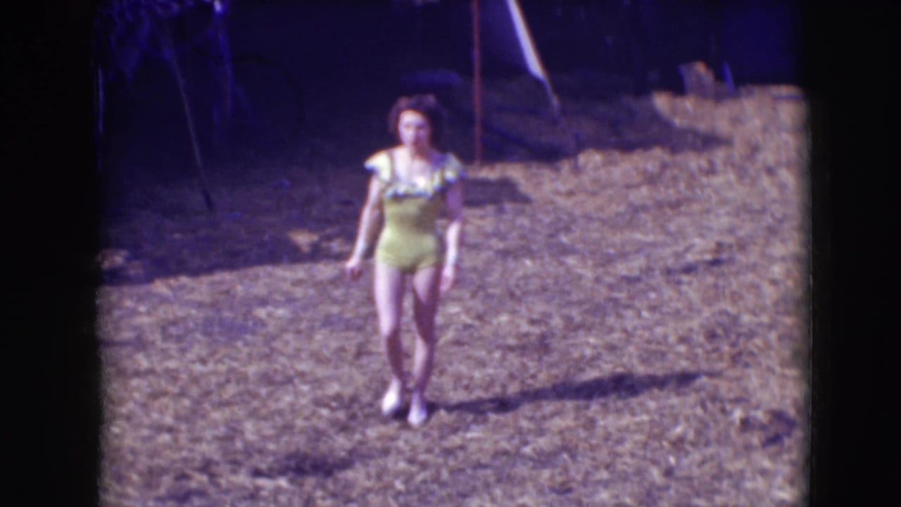 At Ringling Brothers Sarasota in 1948, a female performer in a yellow one-piece costume walks alone across a dry outdoor arena.