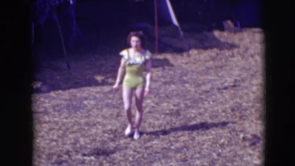 At Ringling Brothers Sarasota in 1948, a female performer in a yellow one-piece costume walks alone across a dry outdoor arena.