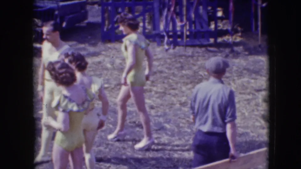 At the 1948 Ringling Brothers Sarasota circus site, costumed female performers stand near a man in trousers and a cap beside arena equipment.