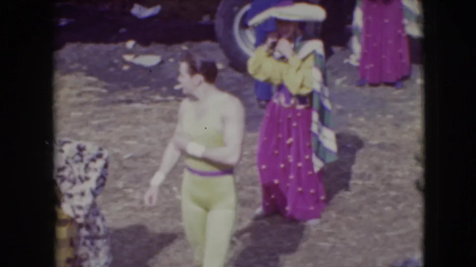 A yellow-leotard performer and a checkered clown appear on the 1948 Ringling Brothers Sarasota circus lot, with other costumed people in the background.