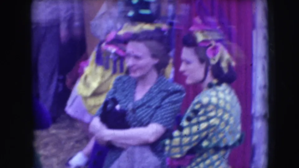 Two women in mid-century dress stand beside costumed performers in 1948 Sarasota circus home-movie footage.