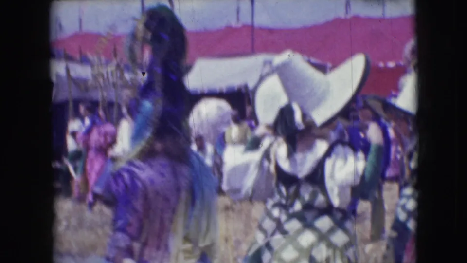 1948 Sarasota circus scene with costumed performers, spectators, tents, and a large white hat seen from a handheld 8mm viewpoint.