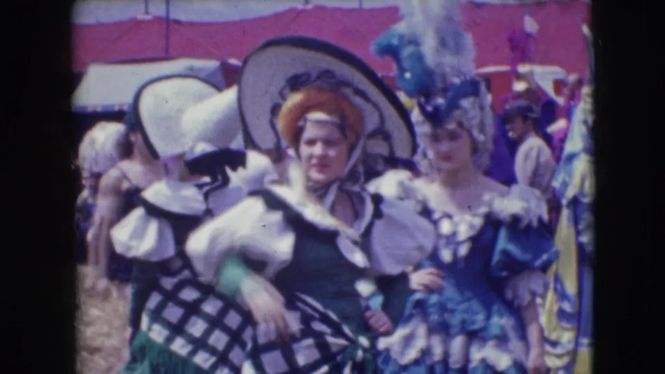 Two costumed adults in large hats and ornate outfits appear amid a crowded 1948 Sarasota outdoor entertainment scene.