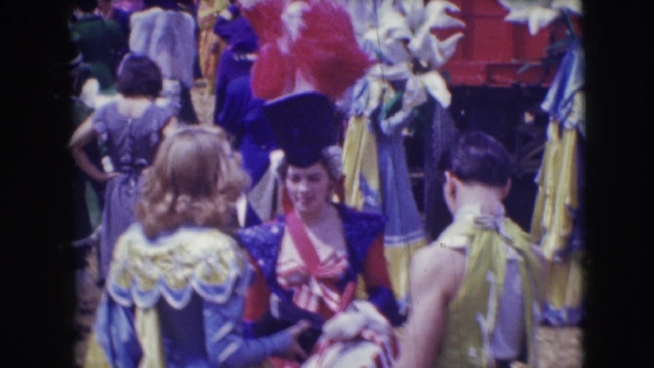 Several costumed circus performers gather in bright red, blue, yellow, and purple outfits.
