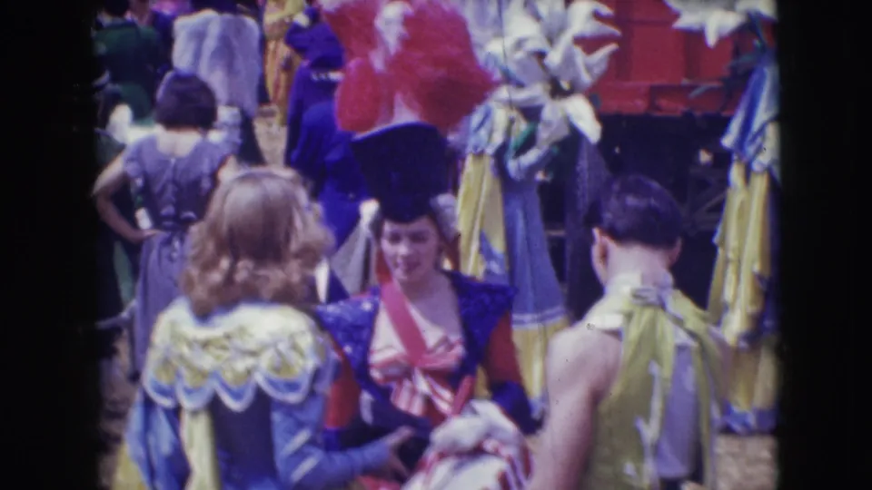 Costumed performers at the Ringling Brothers Sarasota circus gather and converse in colorful outfits with feathered headpieces.