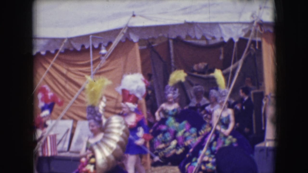 Performers at the Sarasota circus appear backstage under canvas, with feathered hats, sequined dress, and attendants nearby.