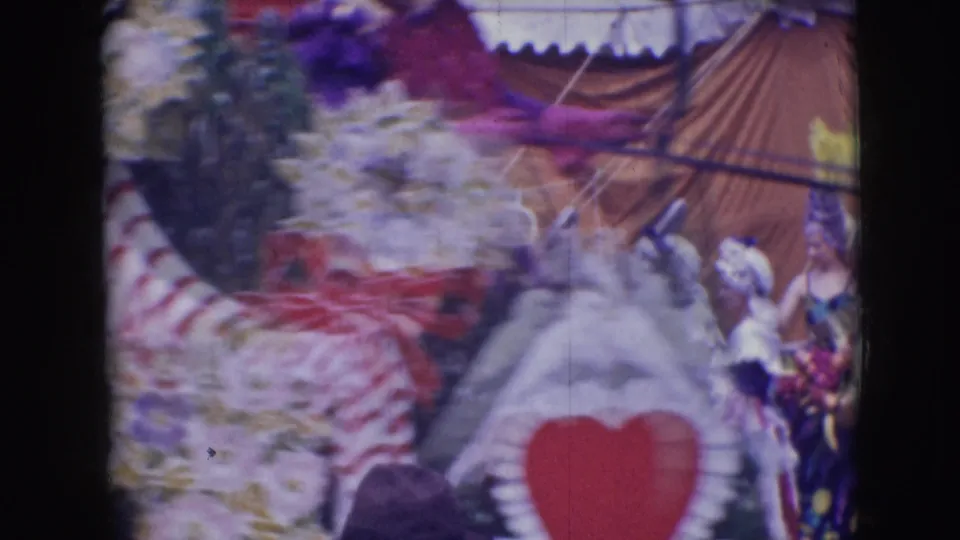 Motion-blurred 8mm frame from the Sarasota circus parade showing a striped form, white bird figure, performers, and tent backdrop.