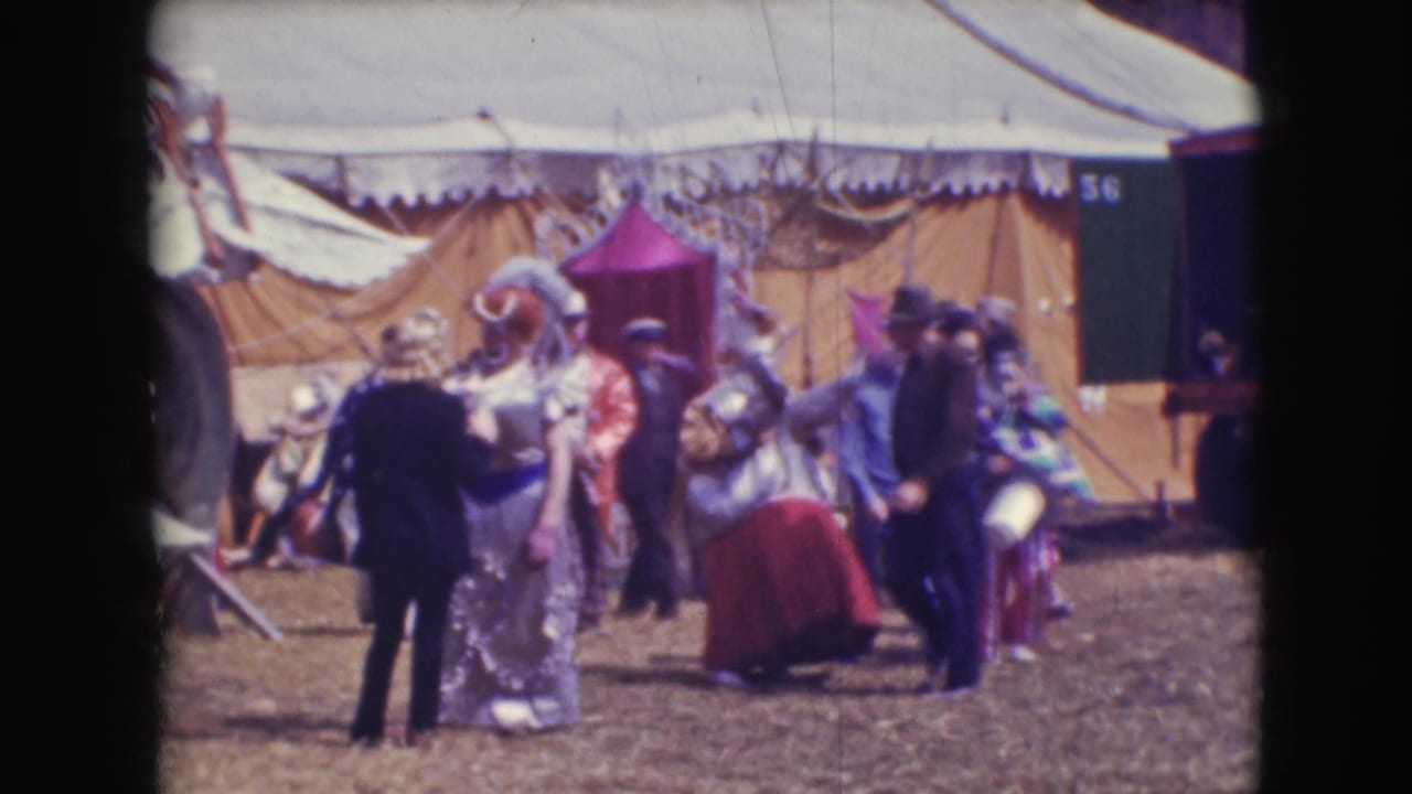 1948 Sarasota circus footage showing clowns in colorful costumes and staff near large canvas tents on a dirt lot.