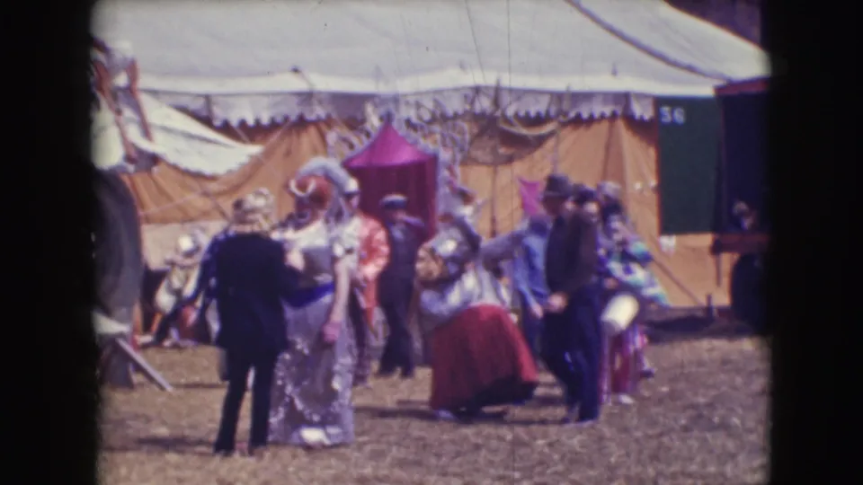 1948 Sarasota circus footage showing clowns in colorful costumes and staff near large canvas tents on a dirt lot.