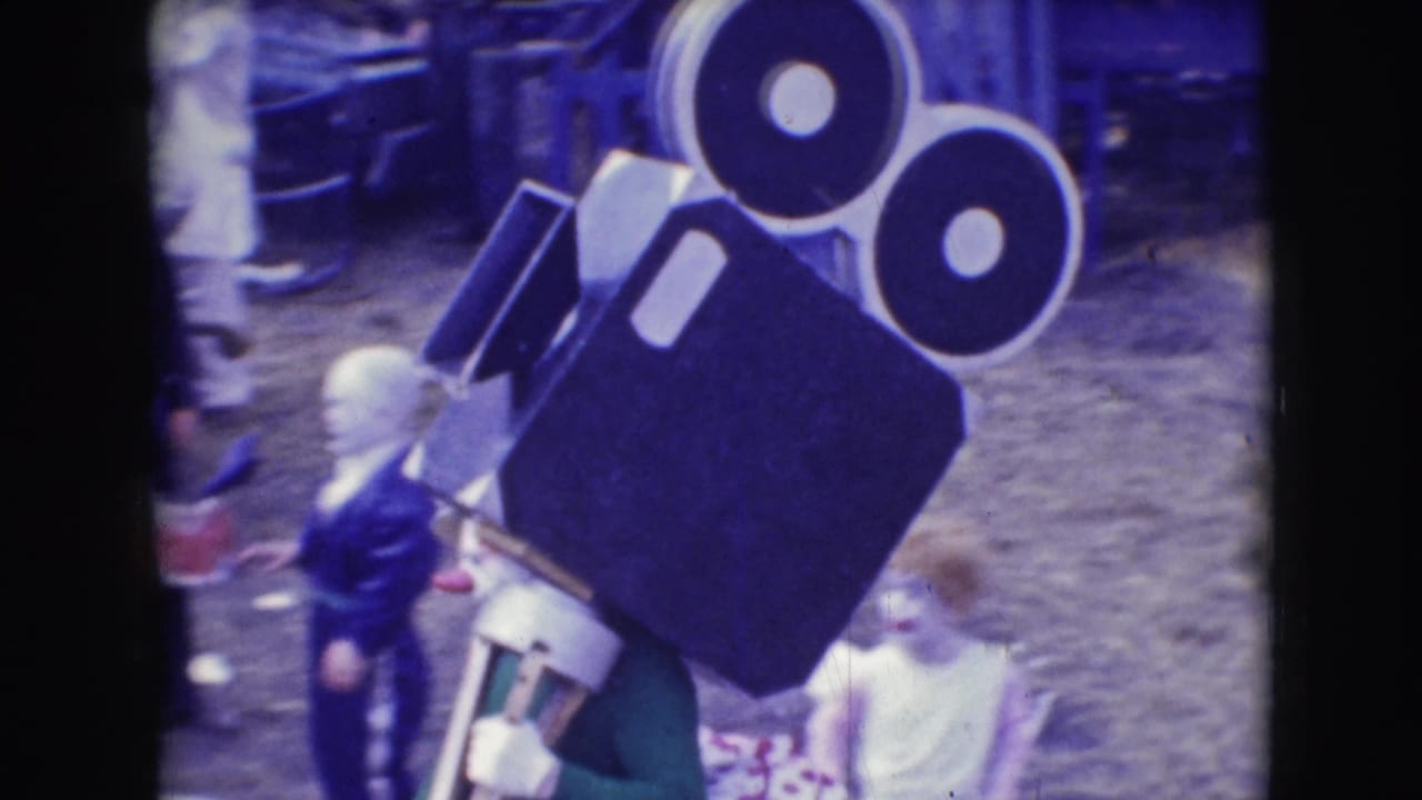 Large film-camera-shaped prop near people at an outdoor circus area.