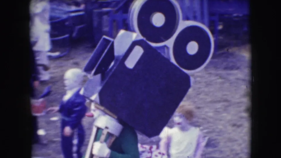 1948 8mm frame from Sarasota circus-event footage showing a large film-camera-shaped prop with people partly visible nearby.