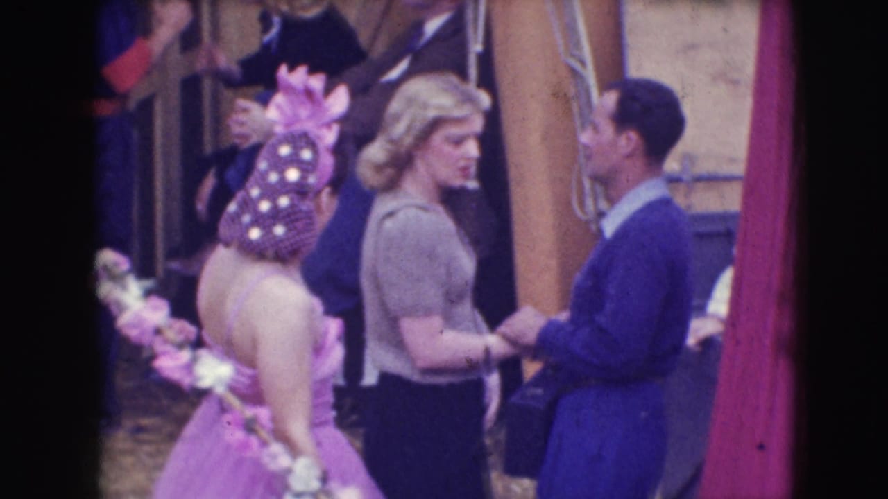 Costumed performers stand near wooden set pieces during a backstage pause.