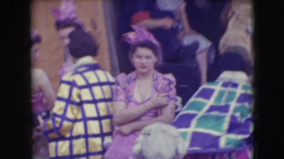 Costumed adults at the Ringling Brothers Sarasota setting gather in patterned coats, pink outfits, and feathered headpieces.