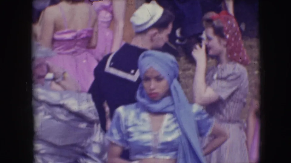 In the Sarasota circus scene, the blue-costumed performer stands near people in a sailor uniform, pink tutu, and patterned dress.