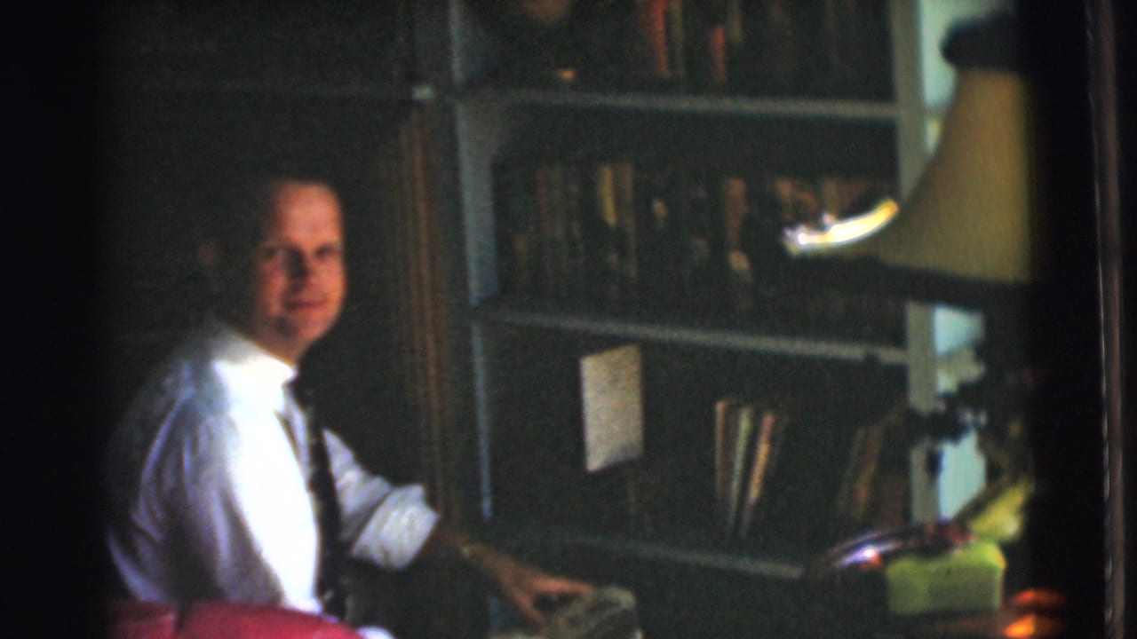 A seated man in a white shirt and tie faces the camera in a Chatham, New Jersey home office setting from 1951.