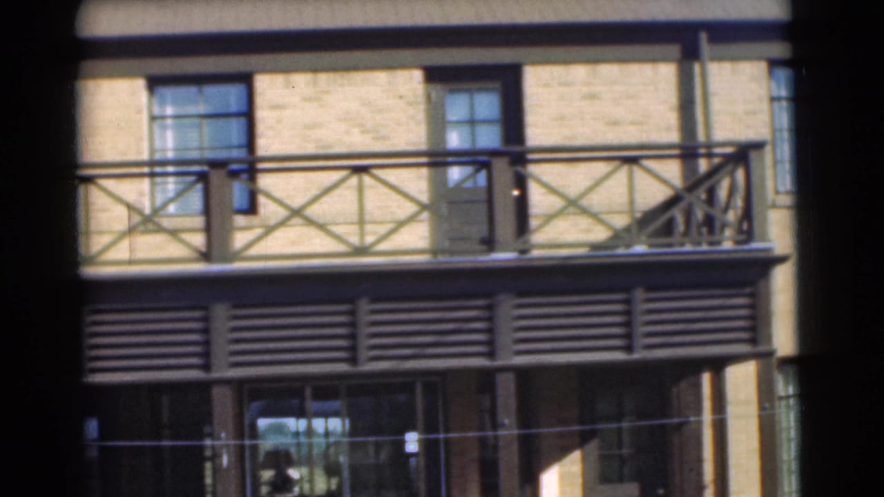 1951 Chatham, New Jersey 8mm frame showing a wider section of brick exterior with balcony railing, louvered band, and large windows.