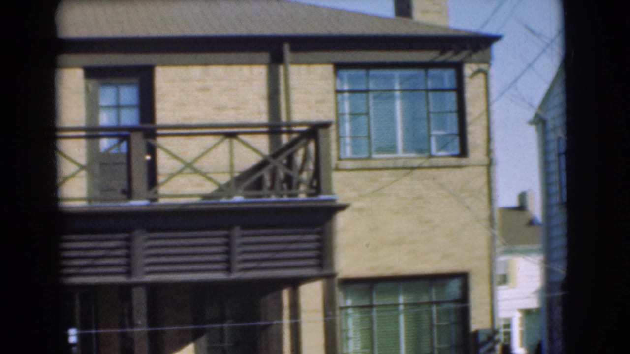 Closer view of yellow brick facade with balcony railing, windows, and dark awning.