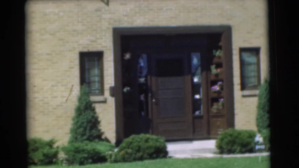1951 Chatham, New Jersey frame showing the front doorway, decorative plant shelves, side windows, lawn, and manicured shrubs.
