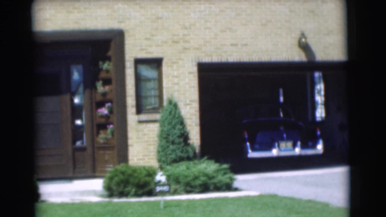 Open garage beside a front door, with the dark car still inside.