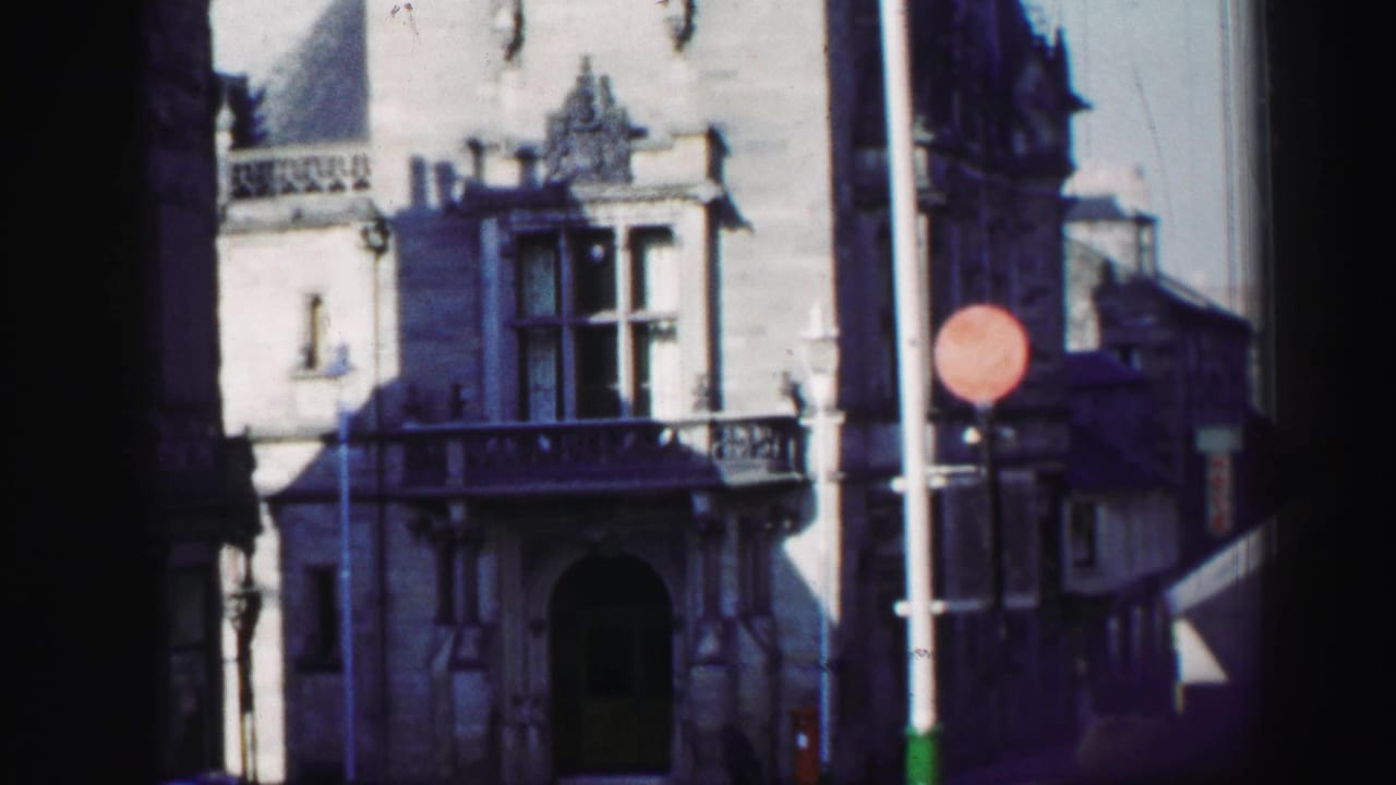 Ornate stone building with arched doorway, balcony, lamppost, and red circular sign.