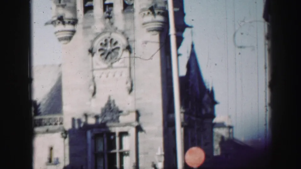 1952 Edinburgh 8mm view of an ornate Gothic Revival stone facade with a round clock face and turret details.