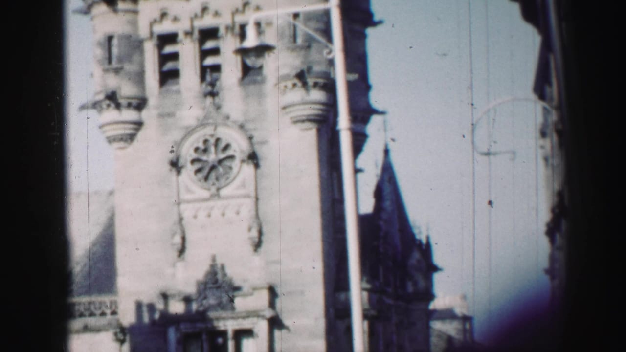 Clock tower facade with turrets and a dark window-like border at center.