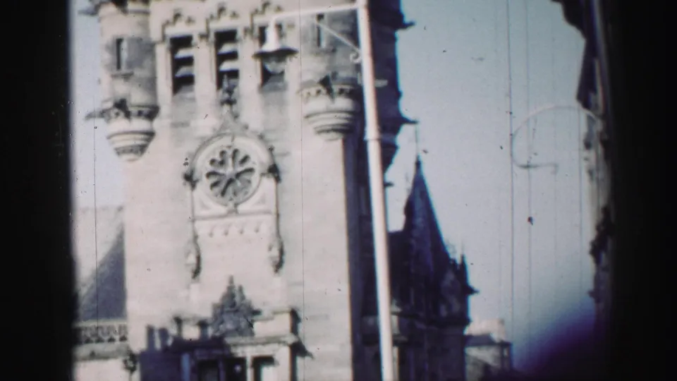 Ornate Edinburgh stone building facade with clock detail, narrow turrets, and dark vertical framing from the camera position.