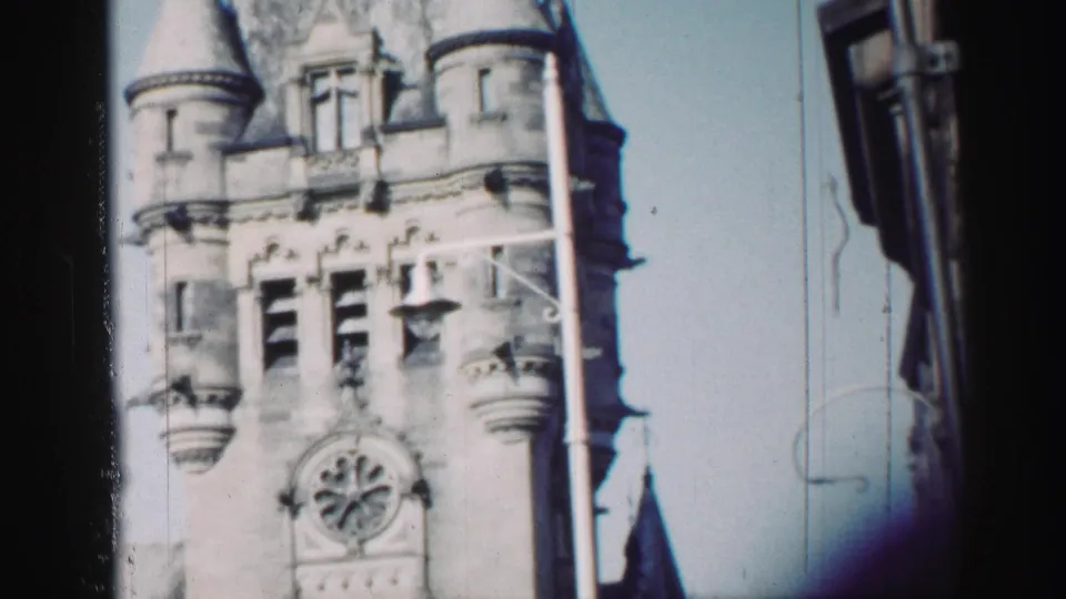 Edinburgh architectural detail in 1952 8mm footage, with a round clock, turreted roofline, and dark framing at the right.