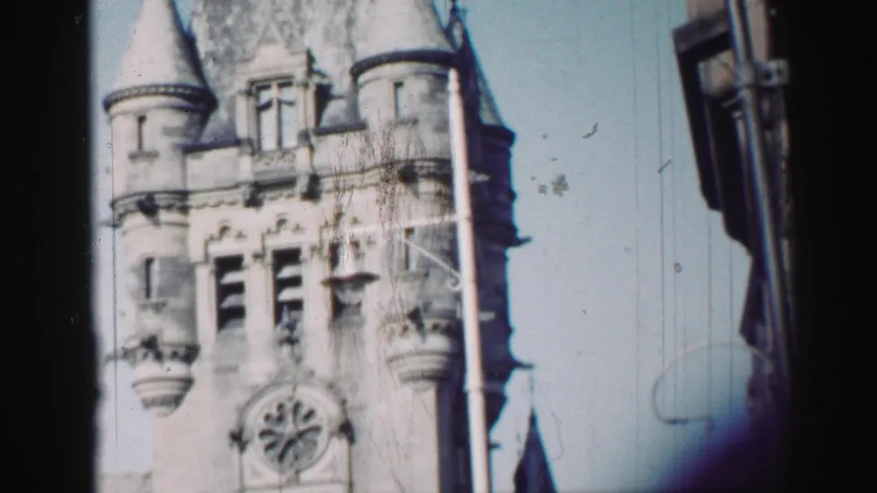 1952 Edinburgh 8mm frame showing a stone church tower with conical turrets, arched openings, and soft film edges.