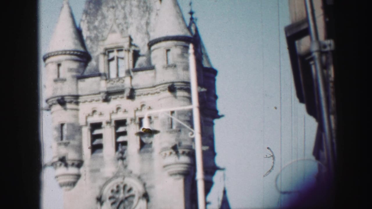 1952 Edinburgh home-movie frame of a Gothic-style church tower, seen from below with a dark street-side edge at right.