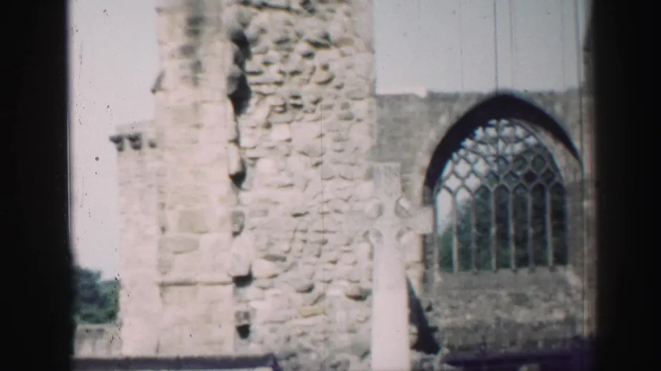 1952 Edinburgh home-movie frame showing the cross and arched church window shifted toward the right as the camera drifts.