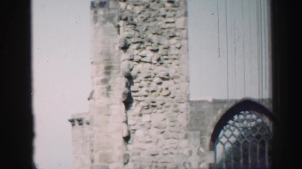 1952 Edinburgh home-movie still with a weathered stone chapel wall, arched tracery window, and visible film scratches.