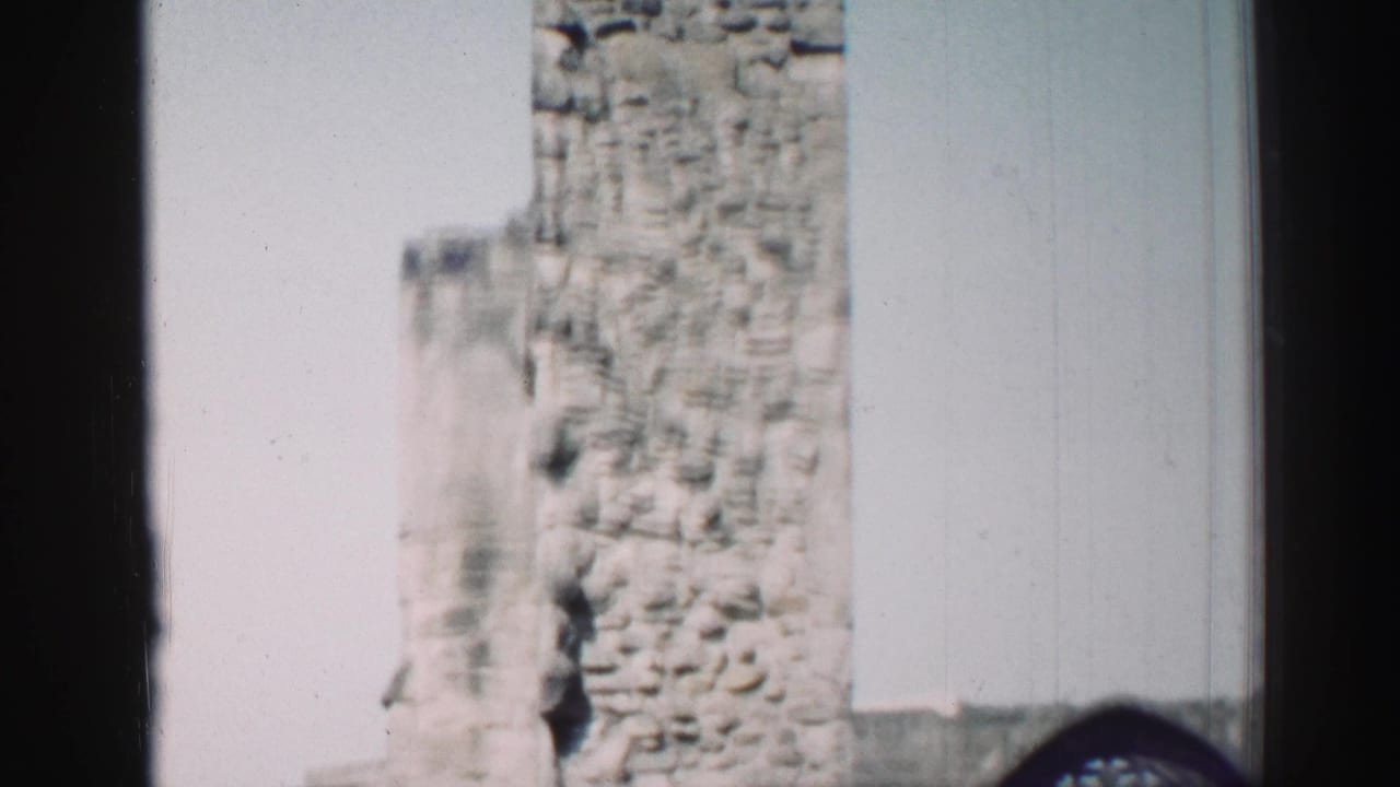 1952 Edinburgh home-movie frame showing a weathered stone church tower partially blocked by a dark vertical foreground edge.