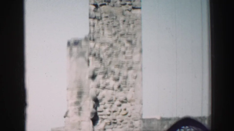 1952 Edinburgh home-movie frame showing a weathered stone church tower partially blocked by a dark vertical foreground edge.