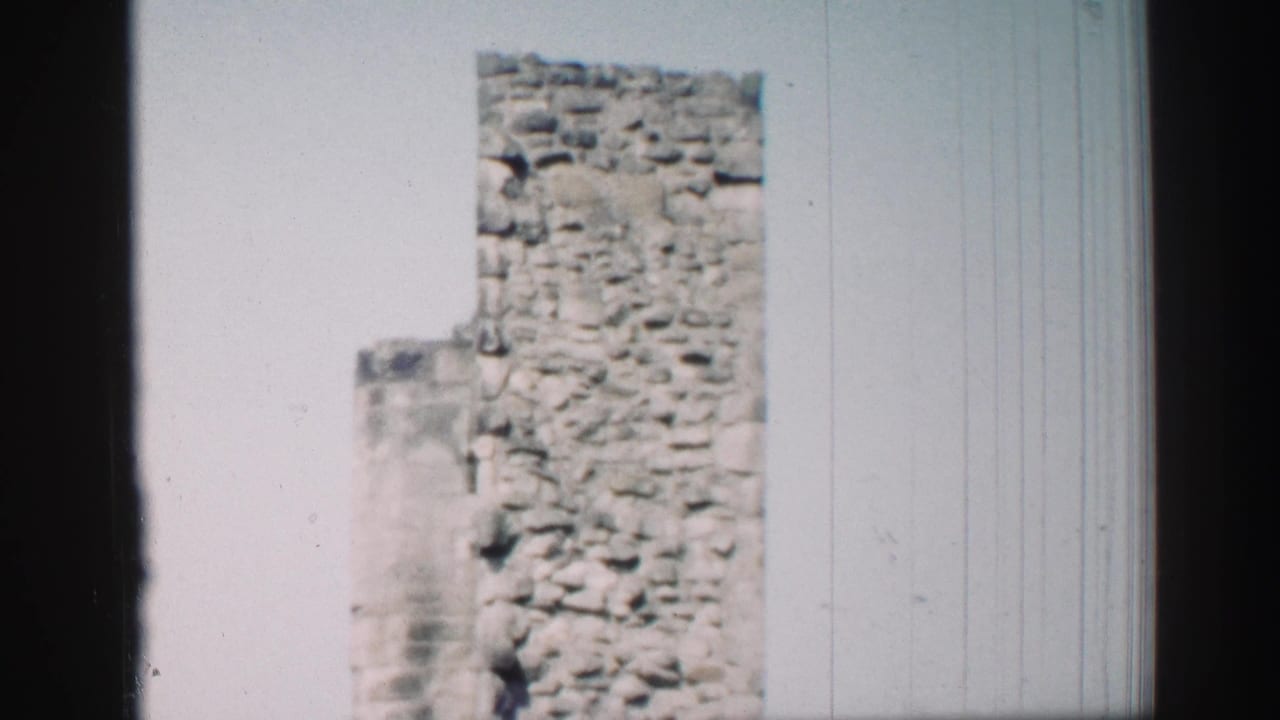 1952 Edinburgh 8mm frame of a historic stone tower and partial church wall under bright daylight.