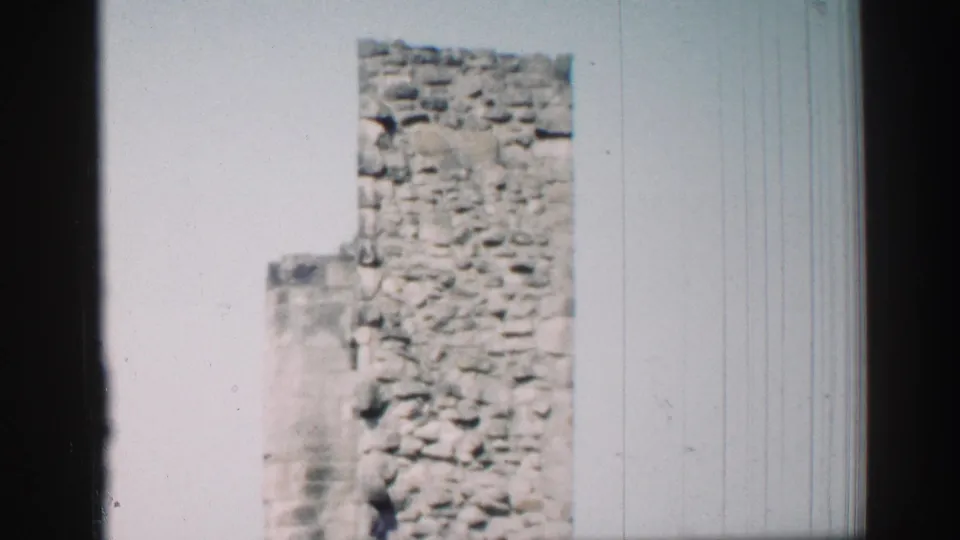 1952 Edinburgh 8mm frame of a historic stone tower and partial church wall under bright daylight.