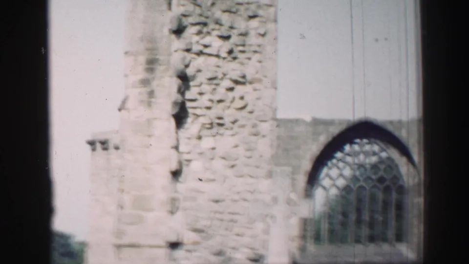 1952 Edinburgh frame showing a weathered church wall and prominent Gothic arched stained-glass window.