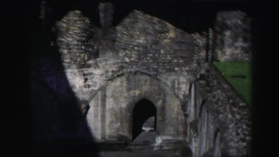 1952 8mm Edinburgh footage showing weathered stone ruins, an arched passage, and rough masonry under uneven light.