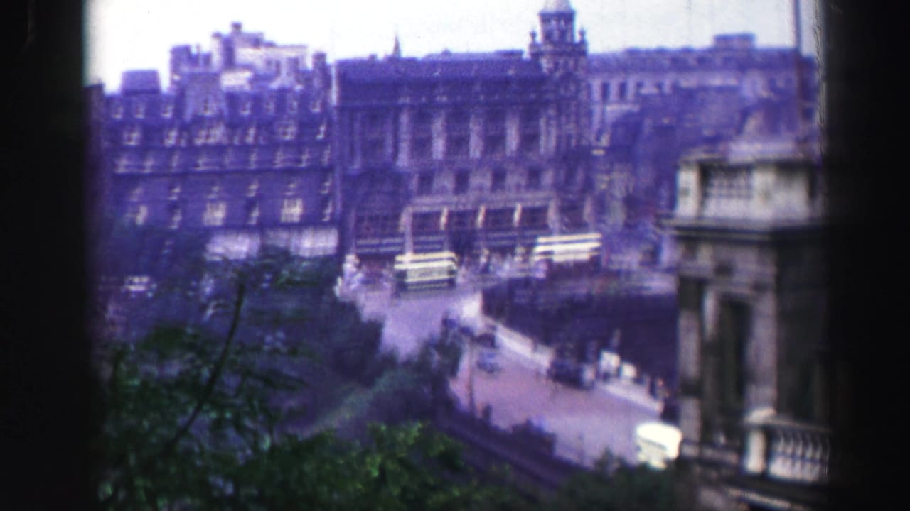 Elevated 1952 Edinburgh view with dark window edges, stone buildings, buses, cars, and a broad city street.