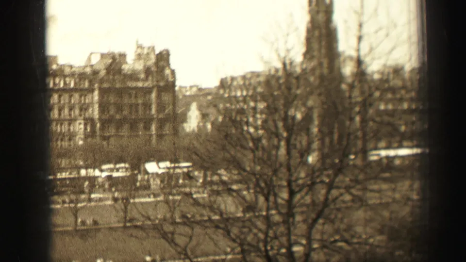 Sepia-toned 1952 Edinburgh street view with bare winter trees, buses, stone buildings, and a tall tower or spire.