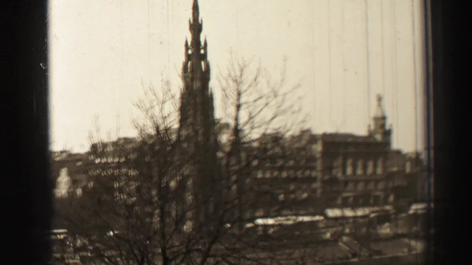 Elevated 1952 Edinburgh view with the Scott Monument behind winter trees and mid-century street traffic below.