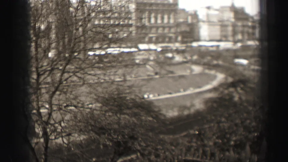 1952 Edinburgh home-movie frame with bare trees, stone architecture, and a broad curved roadway seen through dark window-like borders.