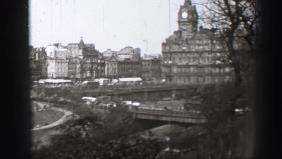 1952 Edinburgh frame with bridge traffic, stone buildings, bare trees, and a prominent clock tower seen from an elevated position.