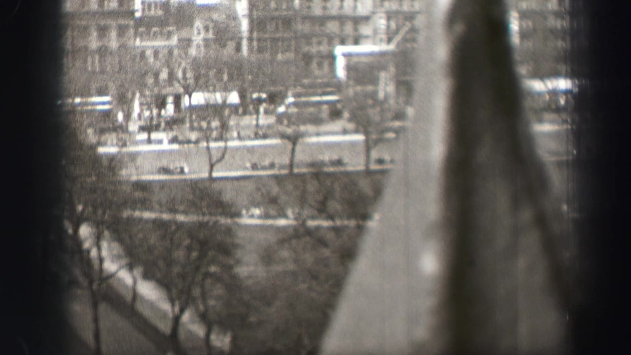 Elevated Edinburgh street view in black and white, with vehicles and pedestrians below and a large blurred vertical shape crossing the foreground.