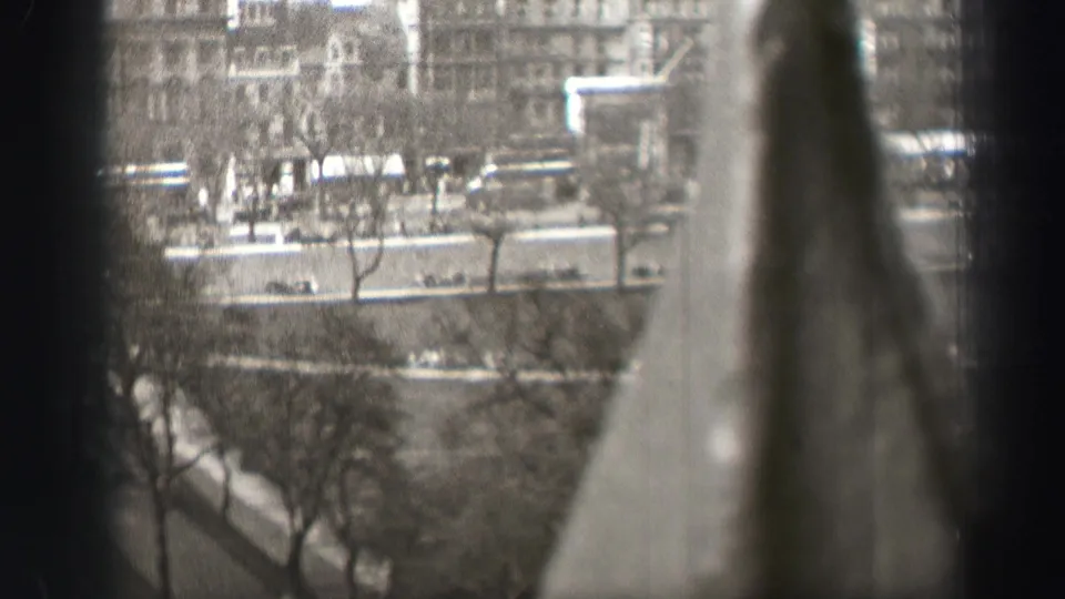 Elevated Edinburgh street view in black and white, with vehicles and pedestrians below and a large blurred vertical shape crossing the foreground.