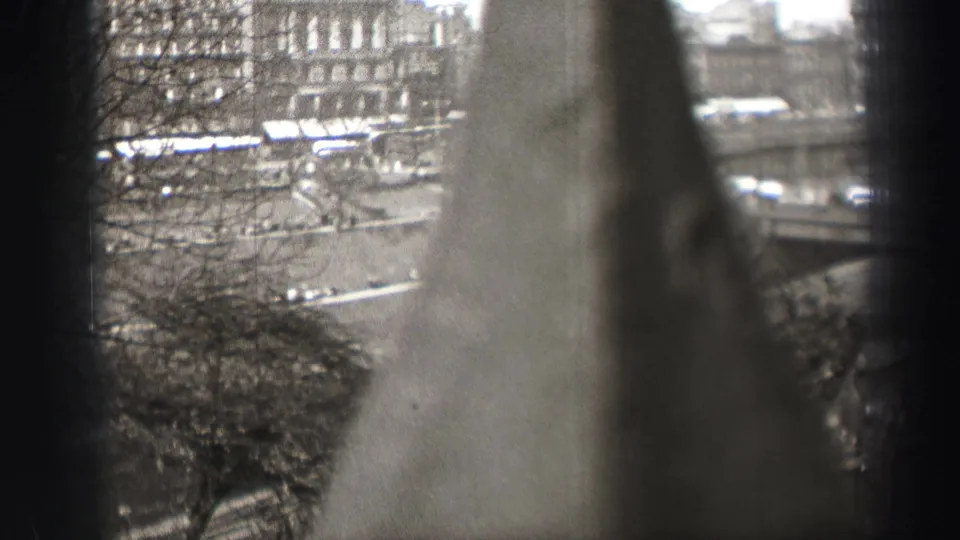 1952 Edinburgh city scene viewed from above through window-like borders, bare trees, and a pale foreground obstruction.